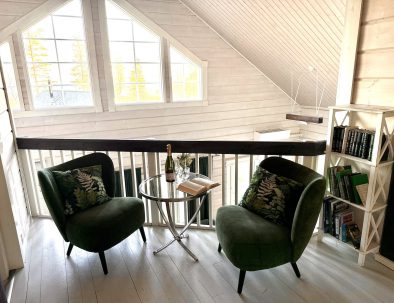 Iltatähden yläkerran lukunurkkaus, jossa on kaksi vihreää nojatuolia, lasipöytä ja kirjahylly