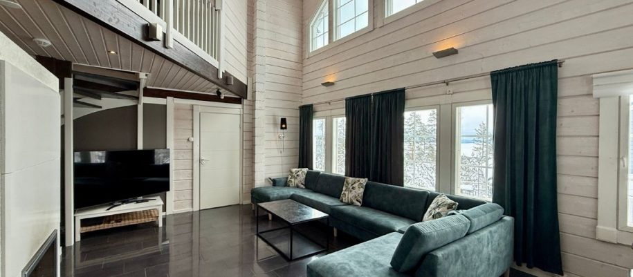 Iltatähti-huvilan oleskelutila. Katto on korkealla, isot maisemaikkunat, suuri kulmasohva